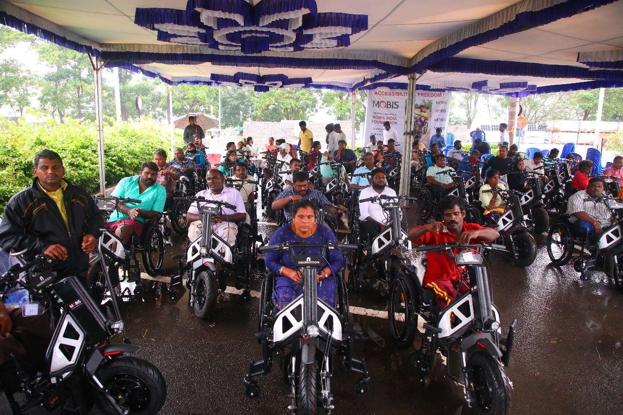 Rows of beneficiaries on new NeoMotion wheelchair bikes at a SMART Foundation distribution event