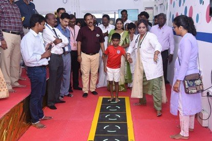 A young boy walks along the interactive gait-training track at the iFIT Hub while doctors and visitors look on